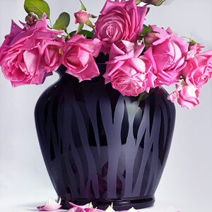 Blumenvase aus schwarzem Glas mit rosa Rosen