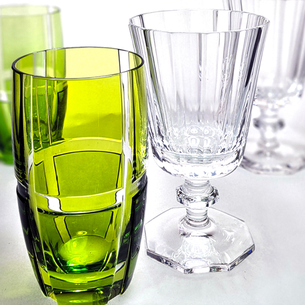 ein grüner Trinkbecher aus Kristallglas und ein Weinglas. Beide mit geschliffenem Dekor.